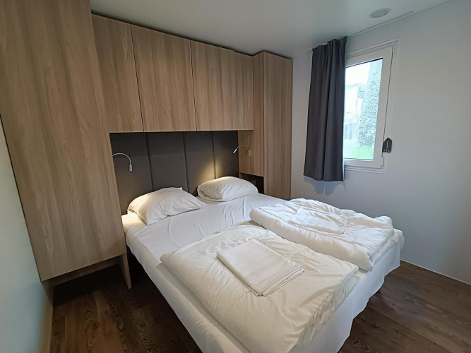 Dormitorio moderno en Grandeur Chalet, Gulperberg, Países Bajos, con cama doble y armarios de madera.