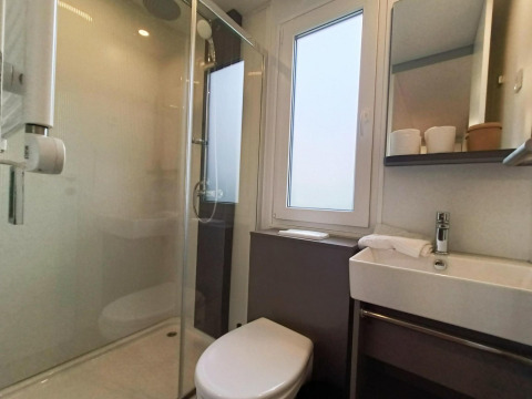 Baño moderno en Grandeur Chalet, Gulperberg, Países Bajos, con ducha, inodoro y lavabo iluminados.