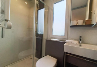 Baño moderno en Grandeur Chalet, Gulperberg, Países Bajos, con ducha, inodoro y lavabo iluminados.