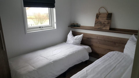 Chambre double moderne au Grandeur Panorama à Gulperberg, Pays-Bas, avec deux lits simples et une fenêtre.