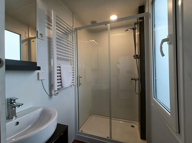 Baño moderno en Grandeur Panorama, Gulperberg, Países Bajos, con ducha, lavabo y ventana grande.