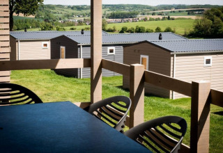 Vue depuis une terrasse de lodge sur des pavillons modernes et des champs verts en arrière-plan rural.