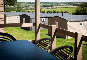 Zicht vanop het terras van een lodge op moderne chalets en groene velden in het landelijke landschap.