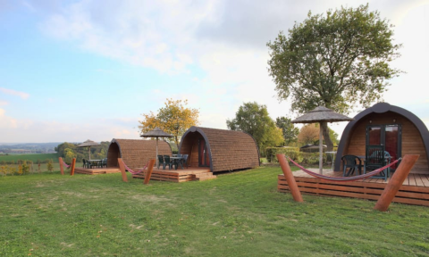 Cabañas de madera con terrazas y hamacas en Woodlodge, Gulperberg, Países Bajos, entorno verde y natural.