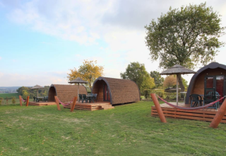 Chalets en bois avec terrasses et hamacs à Woodlodge, Gulperberg, Pays-Bas, dans un cadre verdoyant.