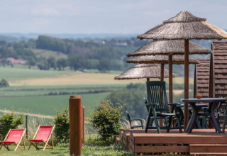 Vue reposante depuis Woodlodge à Gulperberg, Pays-Bas, avec parasols en paille et chaises longues.