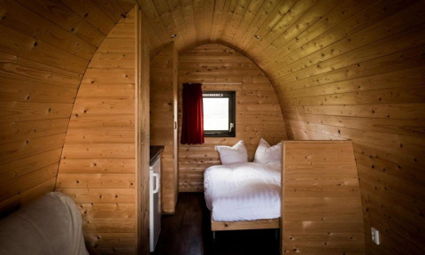 Interior de una acogedora cabaña de madera con cama doble en Woodlodge Gulperberg, Países Bajos.