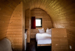 Intérieur d'un lodge en bois chaleureux avec lit double au Woodlodge Gulperberg, Pays-Bas.