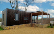 Moderne Bellevue-lodge op Gulperberg in Nederland met houten gevel, stenen basis en overdekte veranda.