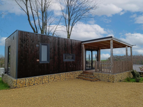 Moderne Bellevue-lodge op Gulperberg in Nederland met houten gevel, stenen basis en overdekte veranda.