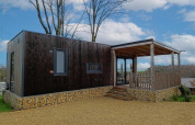 Lodge Bellevue moderne à Gulperberg, Pays-Bas, avec bardage bois, base en pierre et terrasse couverte.