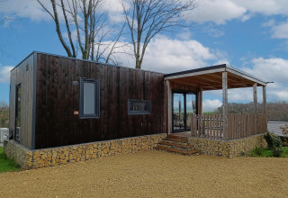 Moderne Bellevue-lodge op Gulperberg in Nederland met houten gevel, stenen basis en overdekte veranda.