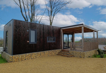 Moderne Bellevue-lodge op Gulperberg in Nederland met houten gevel, stenen basis en overdekte veranda.