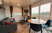 Moderne Bellevue lodge bij Gulperberg, Nederland, met sofa, eettafel en uitzicht op het landschap.