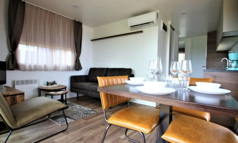 Moderne leef- en eetruimte in lodge Bellevue op Gulperberg, Nederland, met stijlvol meubilair en tafelservies.