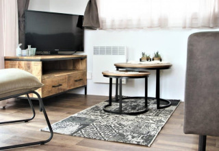 Woonkamer in Lodge Bellevue op de Gulperberg, Nederland, met tv, houten meubels en decoratieplanten.