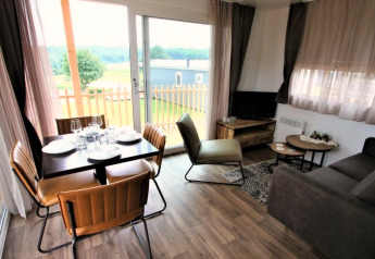 Salotto moderno presso la lodge Bellevue a Gulperberg, Paesi Bassi, con tavolo da pranzo e vista panoramica.