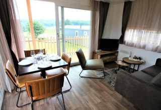 Moderne leefruimte in lodge Bellevue op de Gulperberg, Nederland met eetplek en uitzicht op het groen.