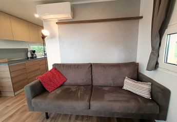 Soggiorno moderno nella lodge Bellevue a Gulperberg, Paesi Bassi, con divano marrone e cucina sullo sfondo.