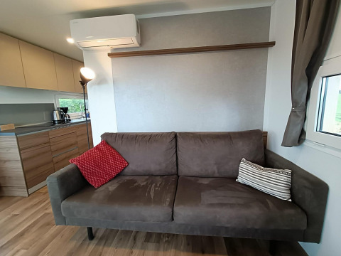 Moderne leefruimte in Bellevue-lodge bij Gulperberg, Nederland, met bruine zetel, kussens en keuken.