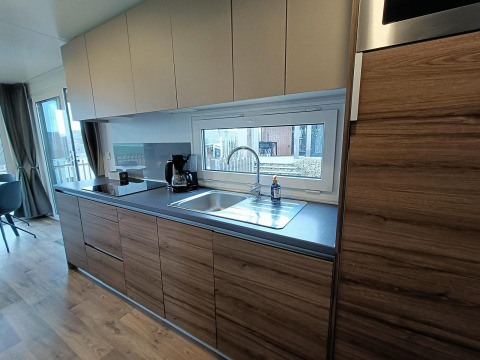 Moderne keuken in lodge Bellevue in Gulperberg, Nederland, met houten kasten en groot raam boven spoelbak.
