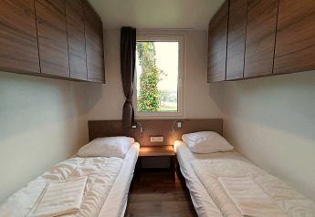 Due letti singoli con armadi in legno e finestra in una camera della Bellevue lodge a Gulperberg, Paesi Bassi.