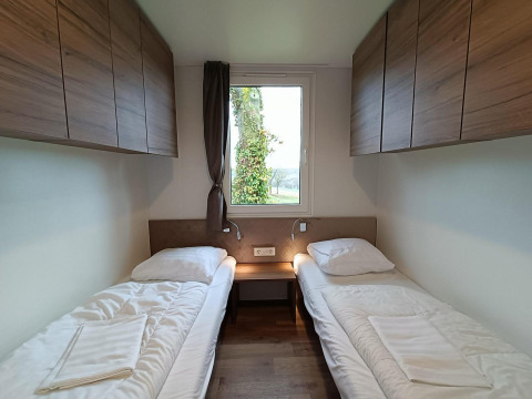 Dos camas individuales con armarios de madera y ventana en la habitación de Bellevue lodge en Gulperberg, Países Bajos.