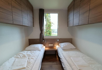 Twee eenpersoonsbedden met houten kasten en raam in een kamer bij Bellevue lodge op Gulperberg, Nederland.