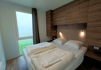 Camera da letto moderna con letto matrimoniale, mobili in legno e luce naturale in Bellevue, Gulperberg.