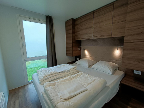 Modern slaapkamerinterieur met tweepersoonsbed, houten kasten en tuinzicht in Bellevue, Gulperberg.