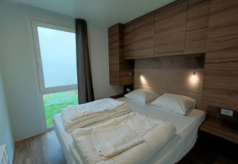 Modern slaapkamerinterieur met tweepersoonsbed, houten kasten en tuinzicht in Bellevue, Gulperberg.