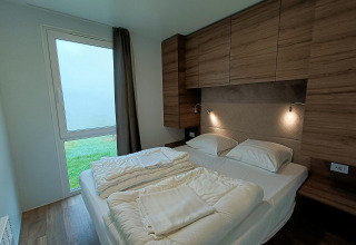 Modern slaapkamerinterieur met tweepersoonsbed, houten kasten en tuinzicht in Bellevue, Gulperberg.