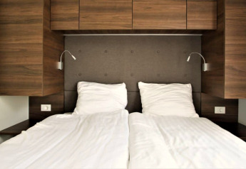 Letto moderno con lenzuola bianche e pannelli in legno al Bellevue di Gulperberg, Paesi Bassi.