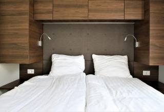 Lit moderne avec draps blancs et panneaux en bois à Bellevue au Gulperberg, Pays-Bas.
