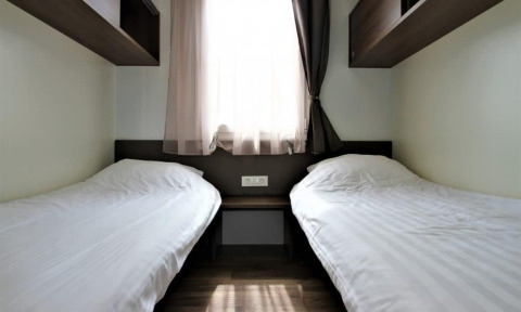 Dos camas individuales con sábanas blancas en una habitación de Bellevue en Gulperberg, Países Bajos.