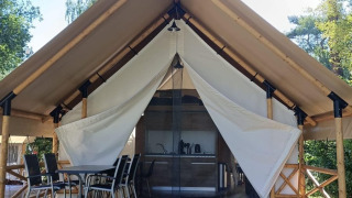 Tenda safari Lodge de Montagne Medium con veranda in legno, sedie da esterno e cucina moderna all'interno.