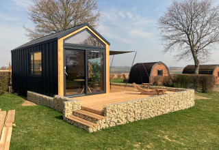 Modernes Tiny House auf Gulperberg in den Niederlanden mit Terrasse, Liegestühlen und malerischer Aussicht.