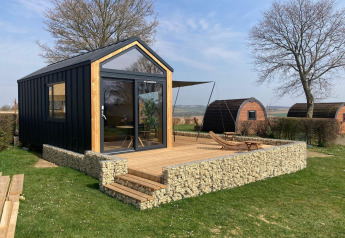 Moderna tiny house lodge en Gulperberg, Países Bajos, con terraza y vistas al campo y otras cabañas.
