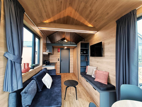 Modernes, helles Wohnzimmer in einem Tiny House am Gulperberg, Niederlande, mit Holzdekor und Sofa.