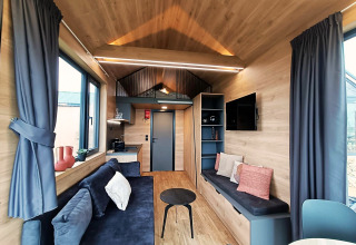 Modernes, helles Wohnzimmer in einem Tiny House am Gulperberg, Niederlande, mit Holzdekor und Sofa.