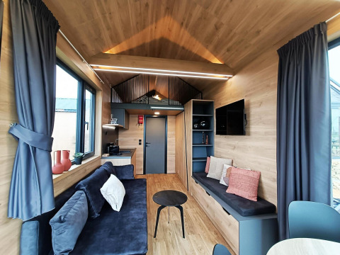 Lichte, moderne leefruimte in een Tiny House op Gulperberg in Nederland met hout en comfortabele zetels.