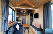 Lichte, moderne leefruimte in een Tiny House op Gulperberg in Nederland met hout en comfortabele zetels.