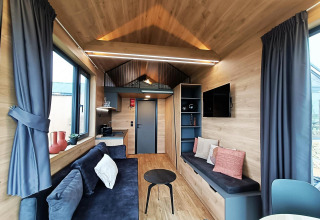Lichte, moderne leefruimte in een Tiny House op Gulperberg in Nederland met hout en comfortabele zetels.