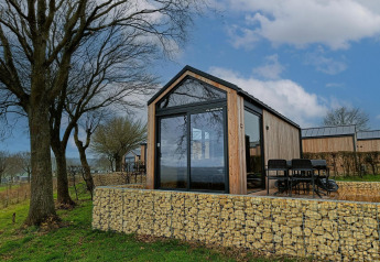 Moderne tiny house lodge ved Gulperberg i Holland, omgivet af natur, træer og stensætninger.