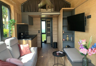 Interieur van een moderne Tiny House lodge op Gulperberg, Nederland, met woonkamer, keuken en loft.