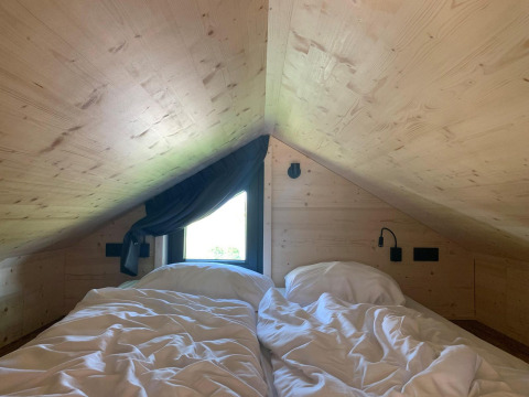 Zolder slaapkamer met tweepersoonsbed en schuin plafond in Tiny House op Gulperberg, Nederland.