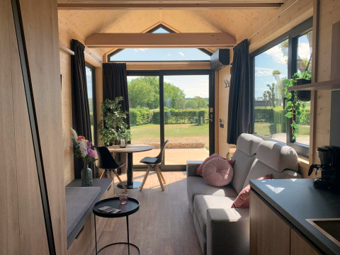 Gemütliche Tiny House Lodge am Gulperberg in den Niederlanden mit Panoramafenstern und hellem Holz.