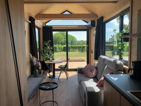 Accogliente Tiny House lodge al Gulperberg nei Paesi Bassi con ampie finestre e interni in legno luminosi.