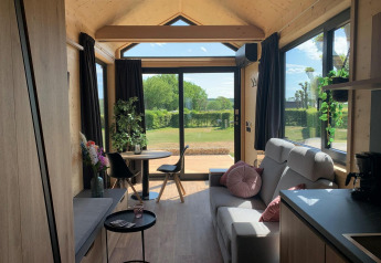 Accogliente Tiny House lodge al Gulperberg nei Paesi Bassi con ampie finestre e interni in legno luminosi.