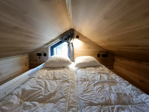 Schlafbereich mit zwei Einzelbetten im Tiny House in Gulperberg, Niederlande, Holz und Dachfenster.